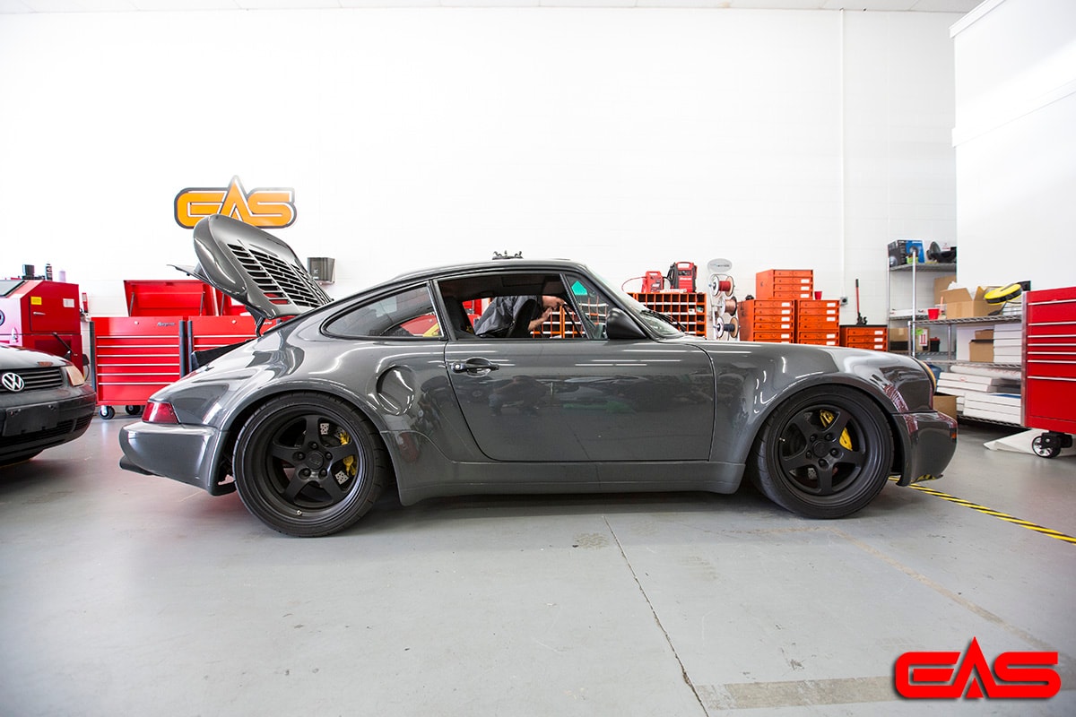 Slate gray Porsche 911 wide-body with black deep-dish wheels and yellow brake calipers
